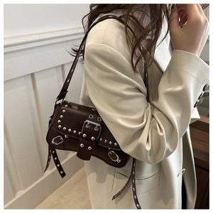 Detail of dark brown leather shoulder bag with silver rivets and punk belt buckles