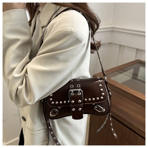 Detail of dark brown leather shoulder bag featuring silver rivets and metal buckle strap