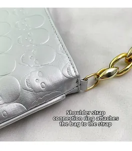 Close-up of metallic silver skull embossed bag with chunky gold chain strap detail