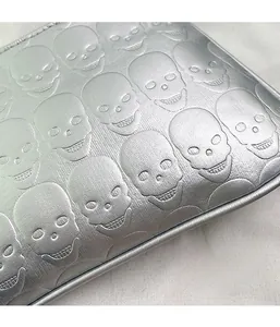 Macro shot of silver pearlescent fabric with skull head embossed patterns and edge detail
