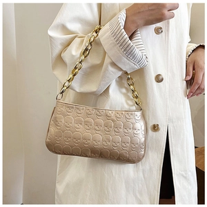 Detailed view of champagne gold skull embossed handbag with thick golden metal chain strap