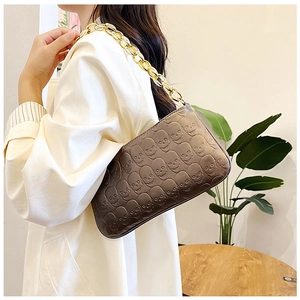 Detailed close-up of brown PU leather shoulder bag featuring embossed skull pattern and gold chain