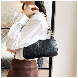 Detail of black embossed skull crossbody bag with chunky gold chain strap decoration