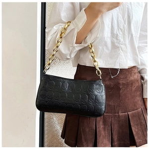 Detail of vintage black skull embossed handbag with thick gold chain on model