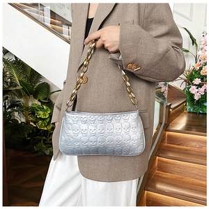 Detail of silver embossed skull pattern bag with chunky gold metal chain strap