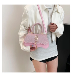 Détail du sac à paillettes roses avec pompon doré S et base en cuir à bords ondulés