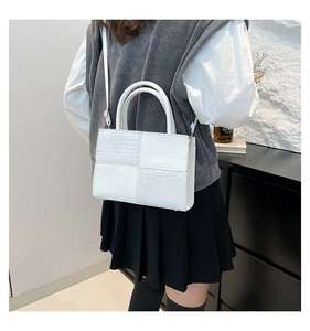 Photo lifestyle d'un sac à main blanc à motif damier crocodile porté par un mannequin