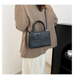Sac bandoulière noir motif crocodile porté avec un costume beige et une jupe blanche