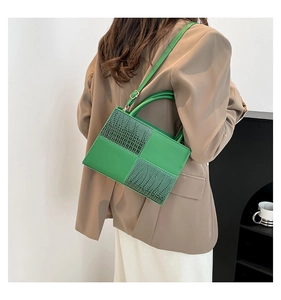 Détail d'un sac à main vert à motif crocodile, patchwork et bandoulière réglable