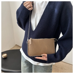 Detail showing the light brown embossed leather texture and silver rivet trim on the bag