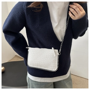 Close-up of white embossed chain bag with silver bead trim and metallic strap detail