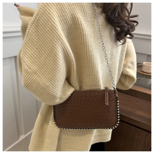 Close-up of dark brown woven crossbody bag with silver chain and metal bead edges