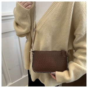 Detail of dark brown woven textured crossbody bag with silver bead trim and chain strap