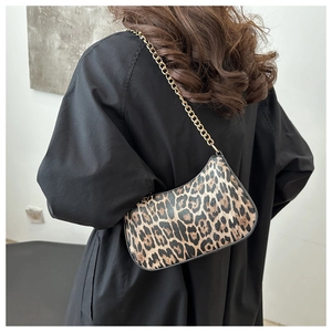 Close-up of leopard print baguette bag with golden chain strap on a model shoulder