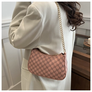 Close-up of crescent bag with monogram M print and stylish gold chain strap detail