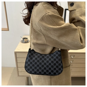 Detail of black leather crescent bag with repeat M pattern and golden chain strap