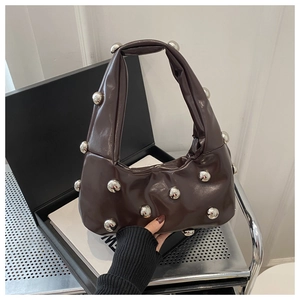 Detail of dark brown pleated crescent bag with silver metallic ball studs and leather texture