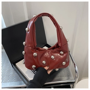Detail of burgundy leather crescent bag featuring prominent silver metallic sphere accents