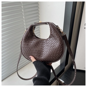 Detail of dark brown woven leather texture and top handle on a crescent hobo bag