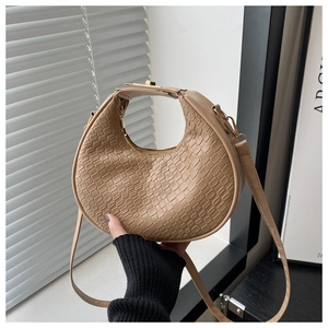 Detail of apricot woven crescent bag featuring metal zipper and adjustable strap