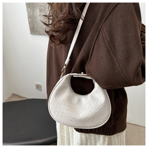 Close-up of white woven texture and metallic gold buckle on the stylish half-moon bag