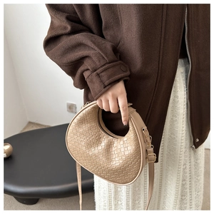 Detail of beige woven hobo bag showing checkered texture and elegant gold hardware