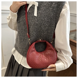 Detail of red woven texture on a crescent shoulder bag with a metallic buckle strap