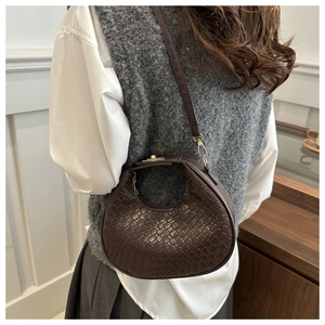 Detail of dark brown woven hobo bag with gold metal buckle shown on a model