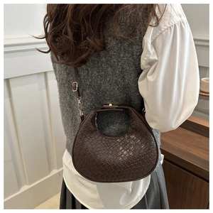 Gros plan sur le sac croissant tissé marron foncé avec boucle métallique dorée chic