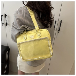 Détail du sac ita jaune avec fenêtre transparente et logo cœur sur cuir PU souple