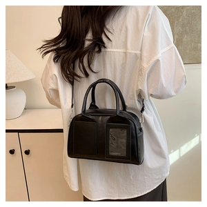 Woman wearing a black Boston shoulder bag with clear card slot and sleek finish