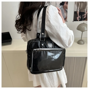 Détail du sac ita noir avec fenêtre transparente en PVC et écusson brodé en forme de cœur