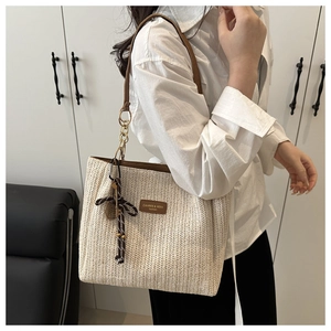 Dettaglio borsa tote in paglia intrecciata con manici in pelle e foulard di seta
