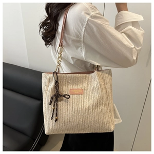 Dettaglio della borsa tote in paglia intrecciata con spallina rosa e catena d'oro