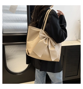 Détail macro du grand nœud beige sur un grand sac cabas en simili cuir souple et brillant