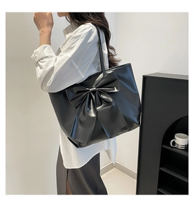 Détail du sac cabas noir mat avec un grand nœud et une texture en cuir premium