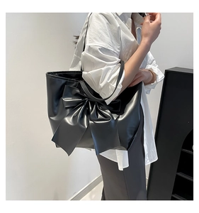 Détail d'un grand sac cabas noir avec un nœud décoratif élégant et une finition en cuir souple