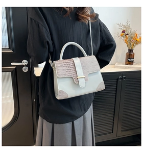 Detail of elegant beige embossed leather handbag with croc-pattern trim and gold hardware