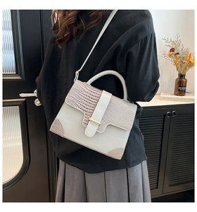 Detail of vintage flap handbag featuring grey leather and pink crocodile pattern accents
