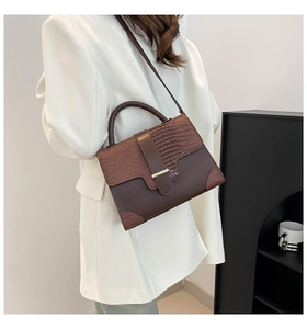 Detail of stylish dark brown crocodile embossed shoulder bag worn by a model