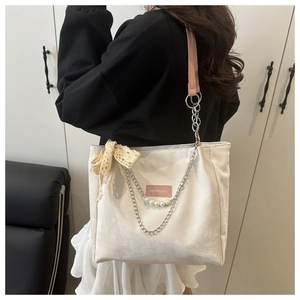 Detailed view of tote bag with lace bow, silver chain, and pearl charms accents