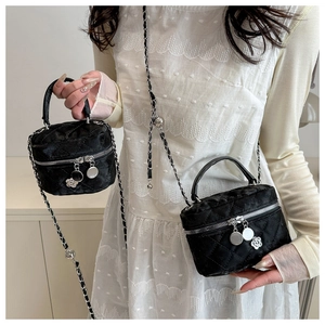 Détail du mini sac seau noir matelassé avec bandoulière chaîne et breloque camélia