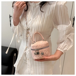 Close-up of pink quilted mini bucket bag with gold chain strap and camellia charm