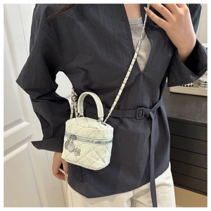 Détail d'un mini sac matelassé vert menthe avec bandoulière chaîne et breloque fleur