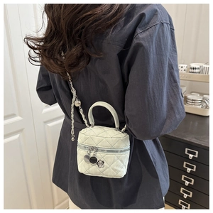 Detail showing white quilted leather mini bucket bag with gold chain strap on a model