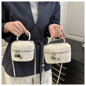 Détail de mini sacs vanity blancs en cuir matelassé avec chaîne et pendentifs fleurs