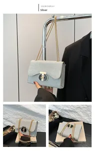 Détail du sac bandoulière argenté scintillant avec chaîne dorée et fermoir noir rond