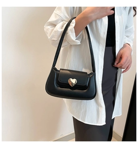 Detail of minimalist black underarm bag with a golden heart-shaped metal buckle clasp