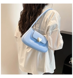Detail of light blue leather underarm bag with a heart-shaped silver metal buckle closure