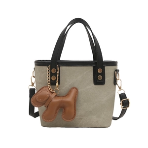 Gray canvas bucket bag with black leather handles and a brown puppy bag charm